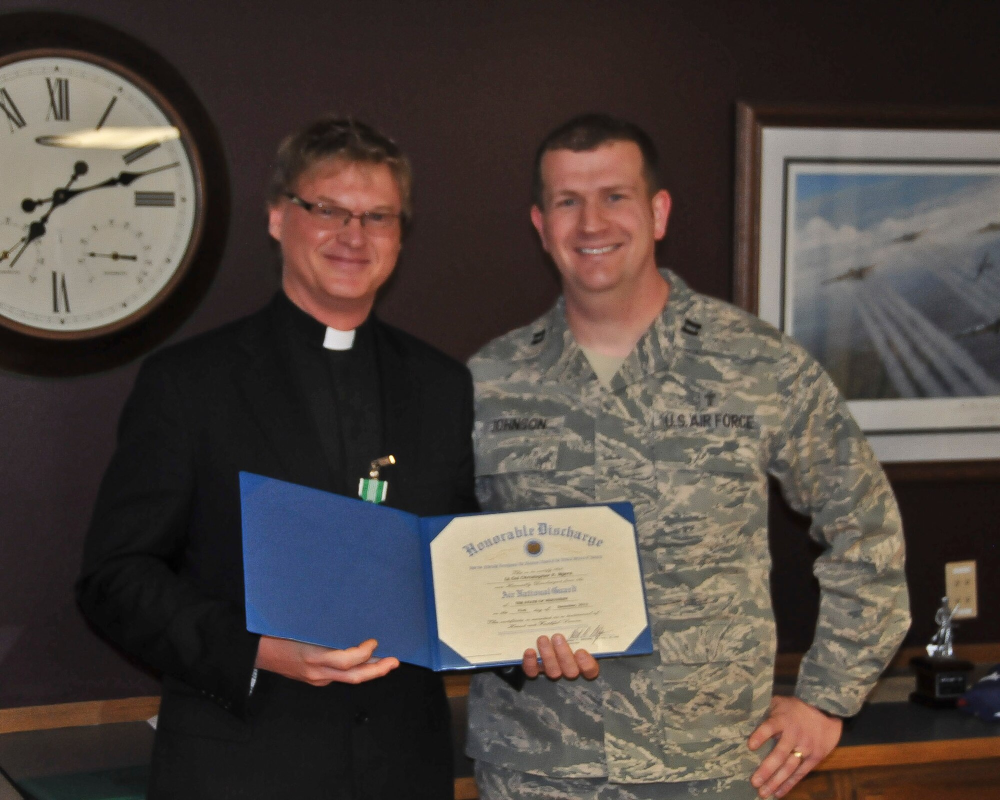 Chaplain Ben Johnson of the 128th Air Refueling Wing presents Chaplain Christopher Myers with his Honorable Discharge after 26 years of military service. 