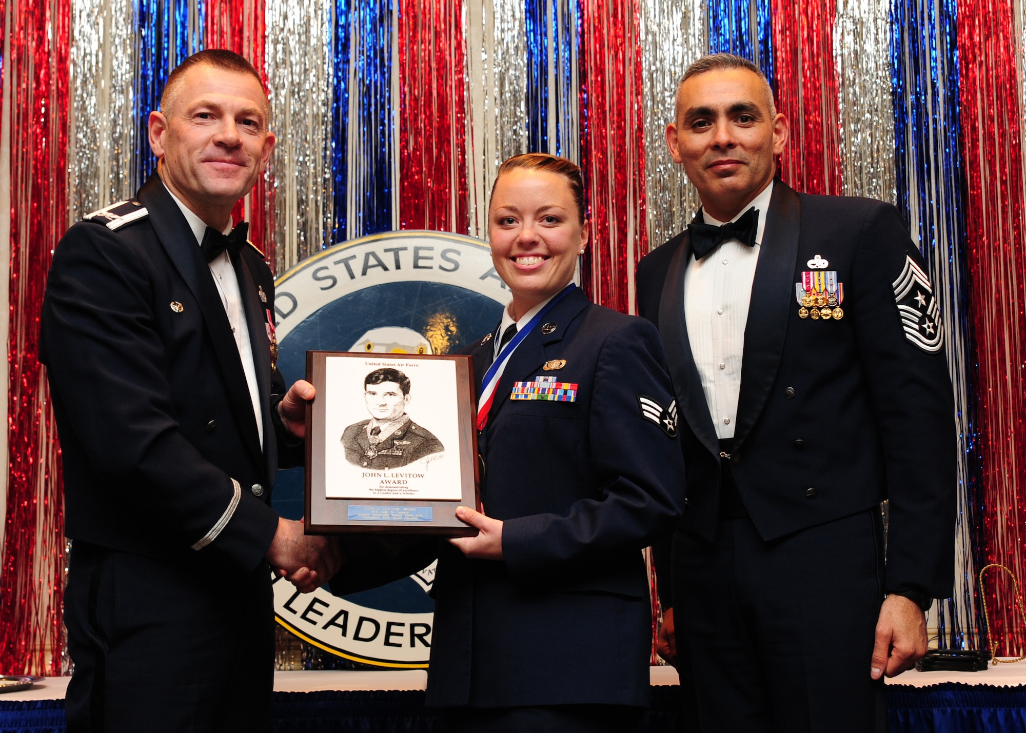 Col. Richard McComb and Chief Master Sgt. Jose LugoSantiago present the John L. Levitow Award to Senior Airman Amy Lexon during the Airman Leadership School Class graduation at Joint Base Charleston - Air Base Feb. 9. The award is presented to the student who displays exemplary excellence as both a leader and a scholar. McComb is the JB Charleston commander and LugoSantiago is the 628th Air Base Wing command chief. Lexon is a Phoenix Raven journeyman assigned to the 628th Security Forces Squadron. (U.S. Air Force photo/Staff Sgt. Katie Gieratz) 

