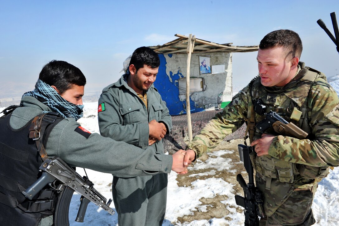 U.S. Army Sgt. Nickolas Mendez, right, shakes hands and talks to Afghan police officers after bringing them new winter boots during a presence patrol in Kabul, Afghanistan, Feb. 9, 2012. Mendez is assigned to the 1186th Military Police Company.