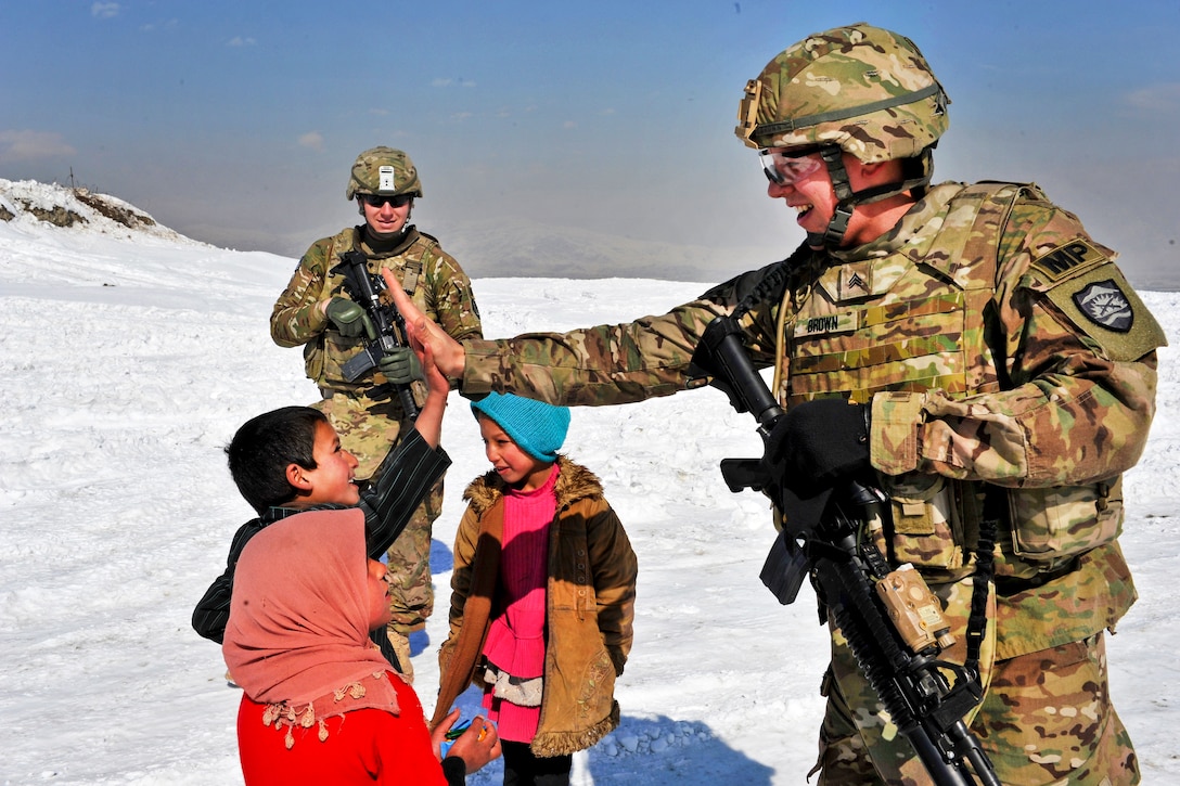 U.S. Army Spc. Trevor Simmons, rear, watches as Sgt. David Brown shares a high five with an Afghan boy during a presence patrol in Kabul, Afghanistan, Feb. 9, 2012. Brown and Simmons are assigned to the 1186th Military Police Company.