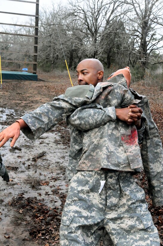An Army National Guard soldier carries a mannequin through the mud during the state-level Best Warrior competition on Camp Swift in Bastrop, Texas, Feb. 4, 2012.