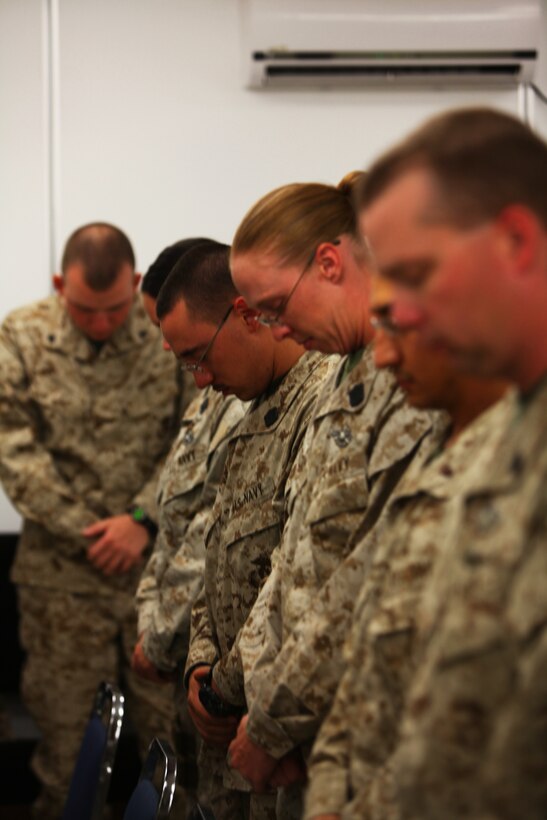 Hospitalmen who work at the Combined Aid Station aboard Camp Leatherneck, Helmand province, bow their heads during a prayer lead by Lt. Edward H. Erwin, a chaplain with Regional Command Southwest, at the ribbon cutting ceremony for the opening of the bases new CAS and Wounded Warrior berthing area, June 16. The new CAS and berthing area provides more space for the hospitalmen to work in, and more privacy for patients.