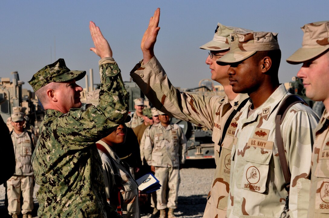 After Master Chief Petty Officer of the Navy Rick West (left) pinned rank insignia on Steelworker 2nd Class Thomas Cunningham, he gave the Seabee from Naval Construction Battalion (NMCB) Four a high five at Camp Leatherneck, Afghanistan, Dec. 8, 2011.