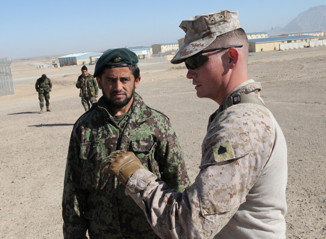 Sgt. Patrick Lynch talks to a member of the Afghan National Army as he prepares to practice a dismounted patrol with other ANA soldiers aboard Forward Operating Base Delaram I, Feb. 14. Marines with Embedded Training Team, Regimental Combat Team 6 have a mission of training and advising members of the ANA.