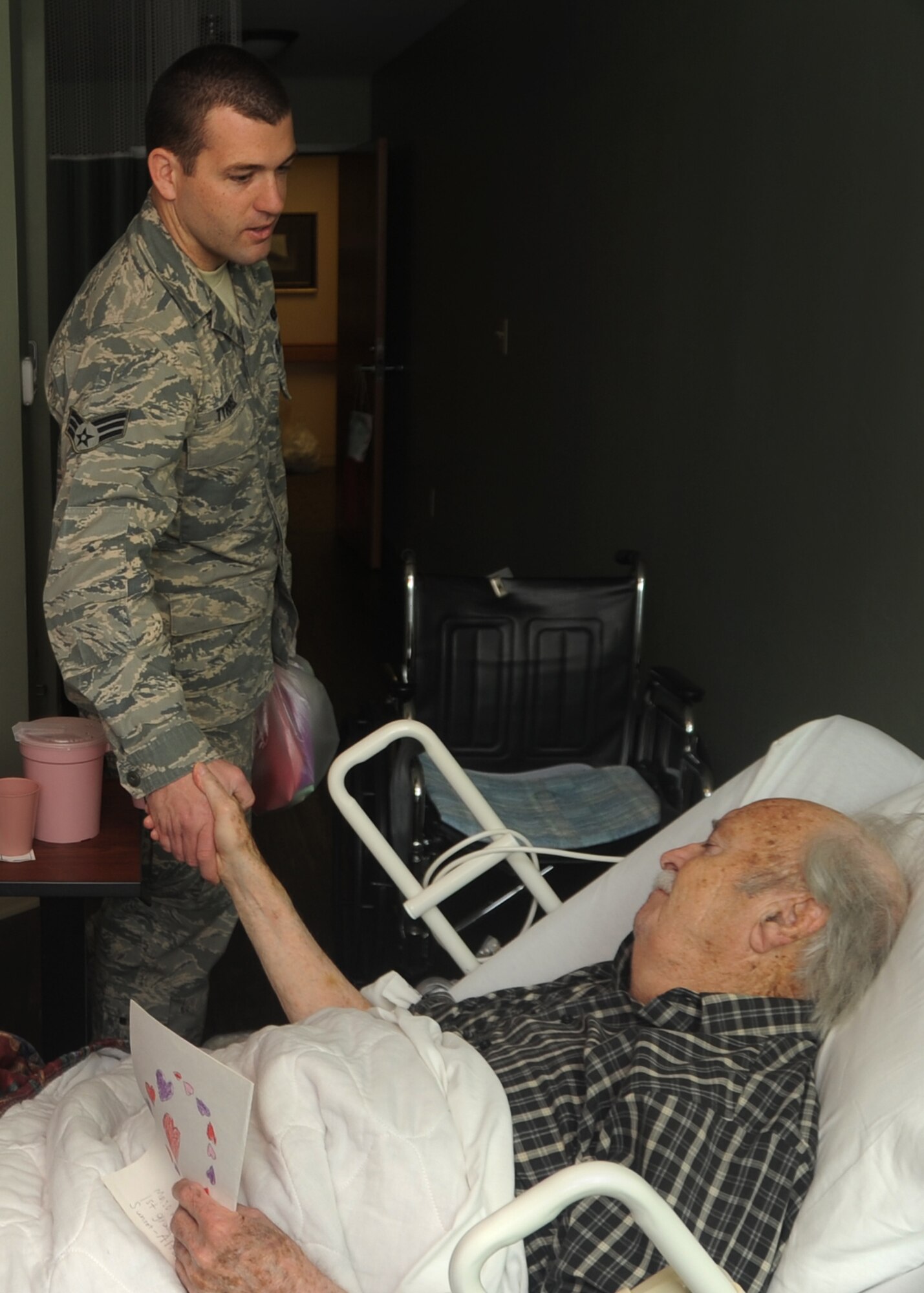 ALTUS, Okla. – Senior Airman Ian Tyrrel, 97th Logistics Readiness Squadron flight service center journeyman, greets retired U.S. Navy veteran Earl Walker, Feb. 14, 2012. Walker served in the Navy under two different contracts. His first was during World War II and then again shortly after the Korean War started. (U.S. Air Force photo by Airman 1st Class Levin Boland / 97th Air Mobility Wing Public Affairs / Released) 