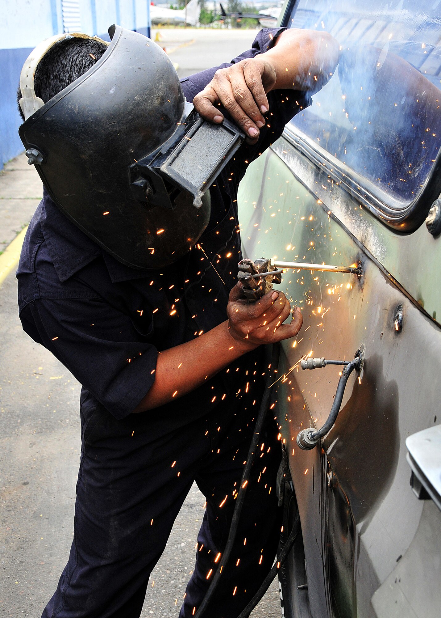 A Honduran Air Force metal worker fixes the holes needed to mount an antennae bracket on the tactical communication vehicle at Col. Hernán Acosta Mejia Air Base, Tegucigalpa, Honduras, Feb. 7.  Approximately 20 members of Air Mobility Command's 571st Mobility Support Advisory Squadron, 615th Contingency Response Wing, Travis AFB, Calif., are participating in a month-long Building Partner Capacity mission in Tegucigalpa, Honduras.  (U.S. Air Force photo by Tech. Sgt. Lesley Waters)