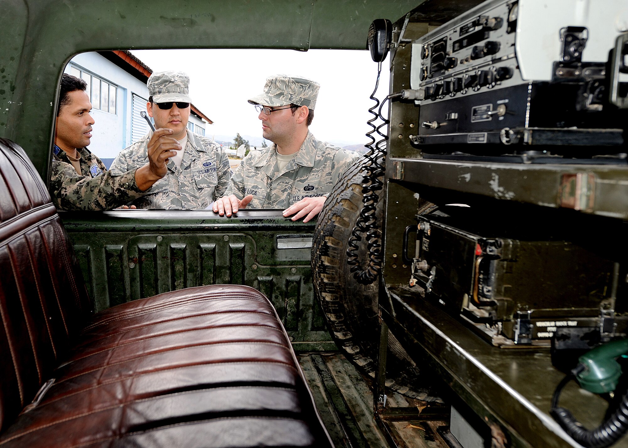 A Honduran Air Force communication technician explains to Tech. Sgt. Claudio Winfree and Tech. Sgt. Brian De Luca, 571st Mobility Support Advisory Squadron air advisors, the different radio capabilities they have in their tactical communication vehicles and use during their missions at Col. Hernán Acosta Mejia Air Base, Tegucigalpa, Honduras, Feb. 7.  (U.S. Air Force photo by Tech. Sgt. Lesley Waters)