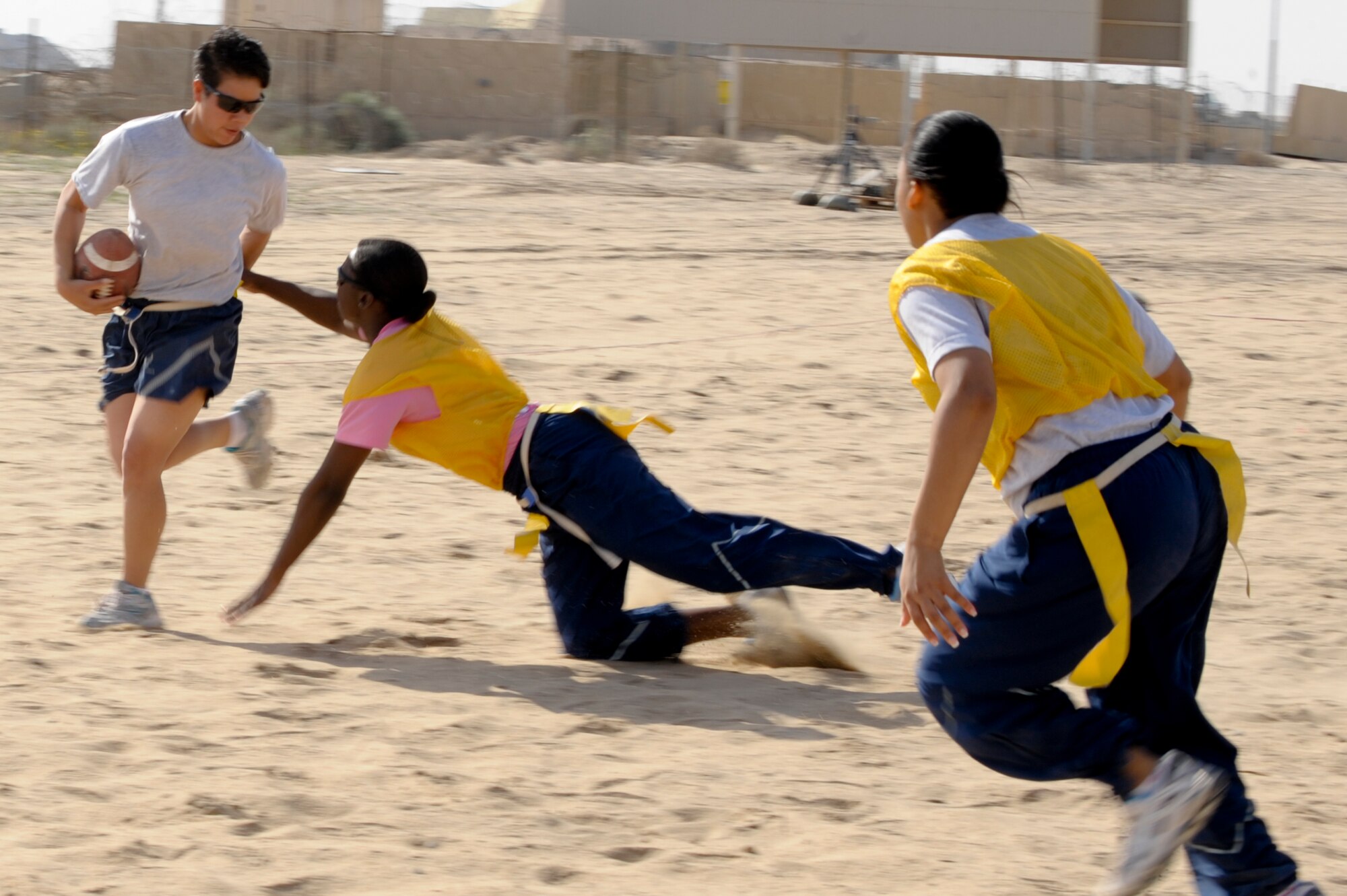 Airman 1st Class Shanity Sugse, 332nd Expeditionary Security Forces Squadron, dodges Capt. Vanessa Jessie, 332nd Expeditionary Force Support Squadron, as she tries to pull her flag during the Valentine’s Day powder puff football game at an undisclosed location in Southwest Asia, Feb 14, 2012. The 332nd EFSS held a variety of sporting events for Valentine's Day. Sugse is deployed from Edwards Air Force Base, Calif., and is a native of Hawaii. Jessie is deployed from Moody Air Force Base, Ga., and is a native of Fayetteville, N.C. (U.S. Air Force photo by Staff Sgt. Joshua J. Garcia/Released)