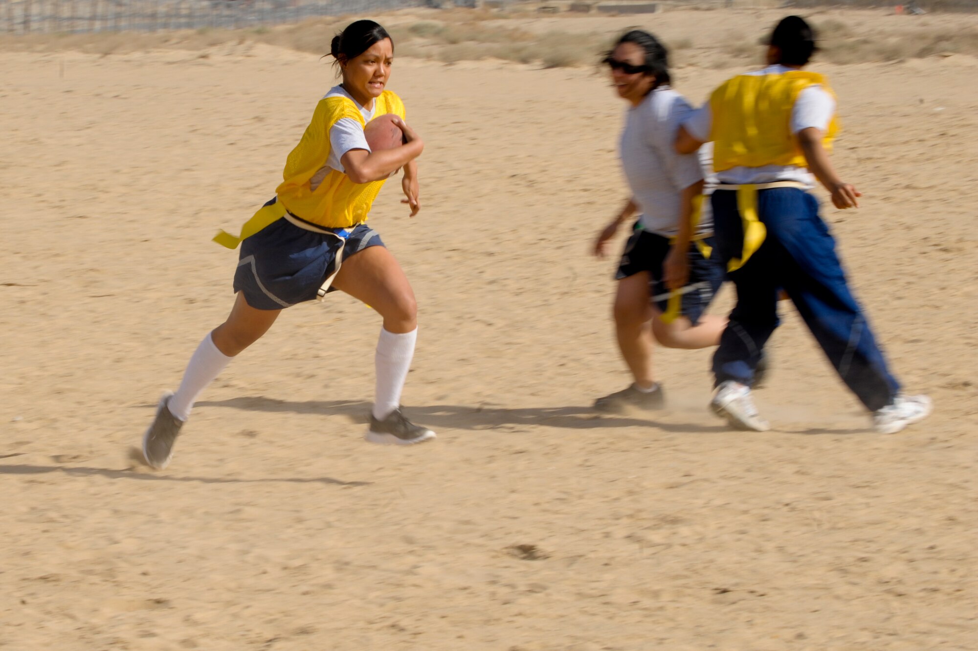 Airman 1st Class Levyann Magcalas, 332nd Expeditionary Communication Squadron, runs the football down the field during a Valentine’s Day powder puff game at an undisclosed location in Southwest Asia, Feb. 14, 2012. Magcalas played quarterback for her team, Angel Cakes. Magcalas is deployed with the Hawaii Air National Guard and is a native of Pahoa, Hawaii. (U.S. Air Force photo by Staff Sgt. Joshua J. Garcia/Released)