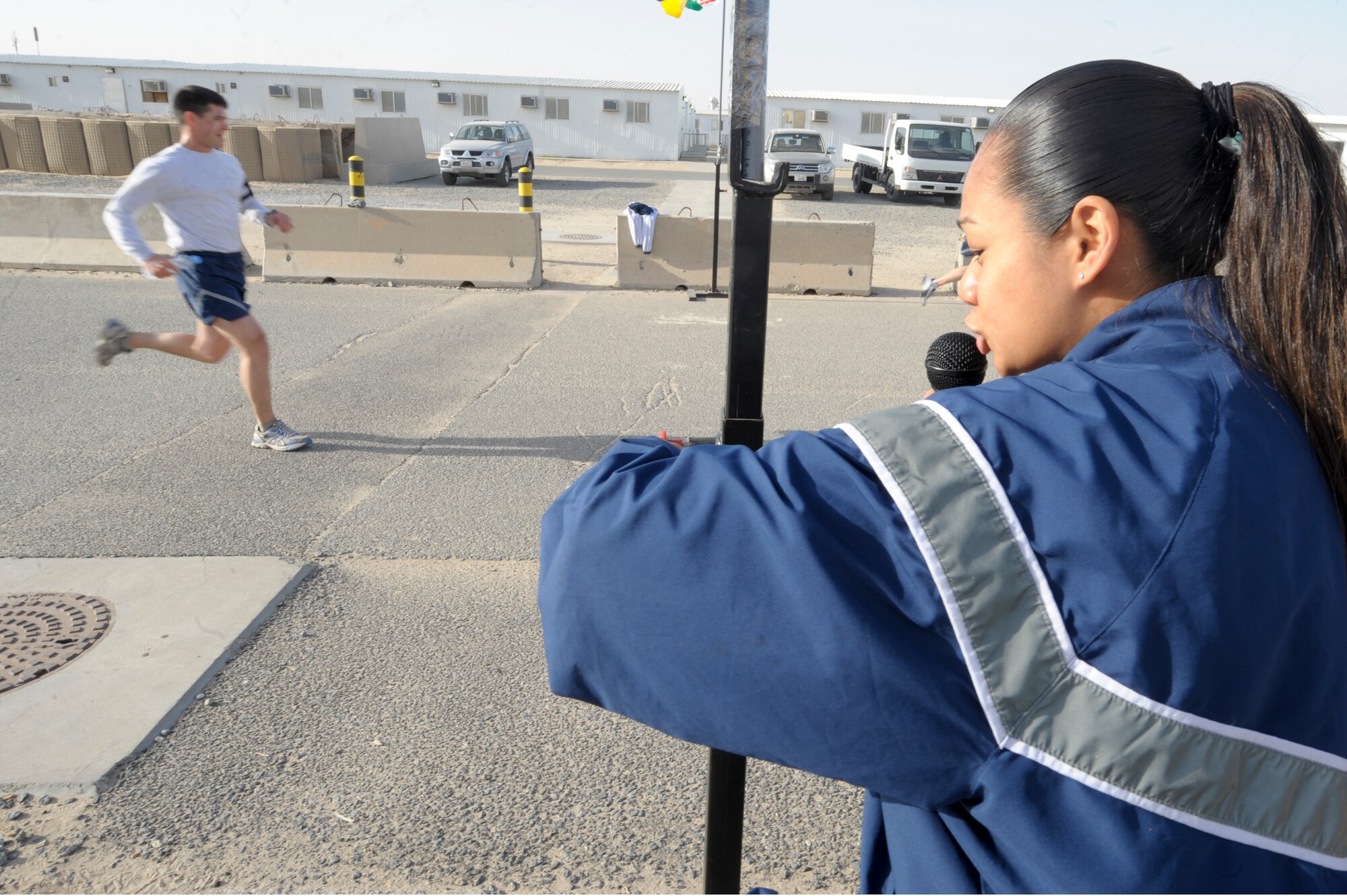 Staff Sgt. Sokum Ouk, 332nd Expeditionary Force Support Squadron, calls out the time as a runner finishes the "Cupid's Love Run" at an undisclosed location in Southwest Asia, Feb. 14, 2012. The top three male and female runners received certificates from the 332nd EFSS. Ouk is deployed from Joint Base Langley Eustis, Va., and is a native of Richmond, Va.(U.S. Air Force photo by Staff Sgt. Joshua J. Garcia/Released)