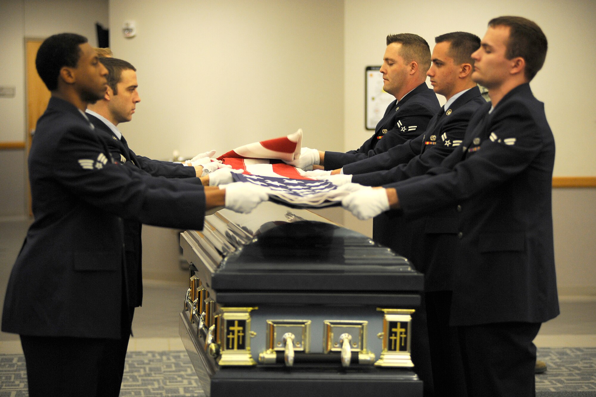 Trainees and members of the 127th Wing Honor Guard fold the U.S. Flag over a casket during a training session at Selfridge Air National Guard Base, Mich., Feb. 10, 2012. In addition to the empty casket, volunteers acted as “grieving family members” to assist honor guard trainees learn the appropriate ceremonial honors to be rendered at a veteran’s funeral. The honor guard held a training session to qualify six new Airmen to serve as members of the unit. (U.S. Air Force photo by John S. Swanson)