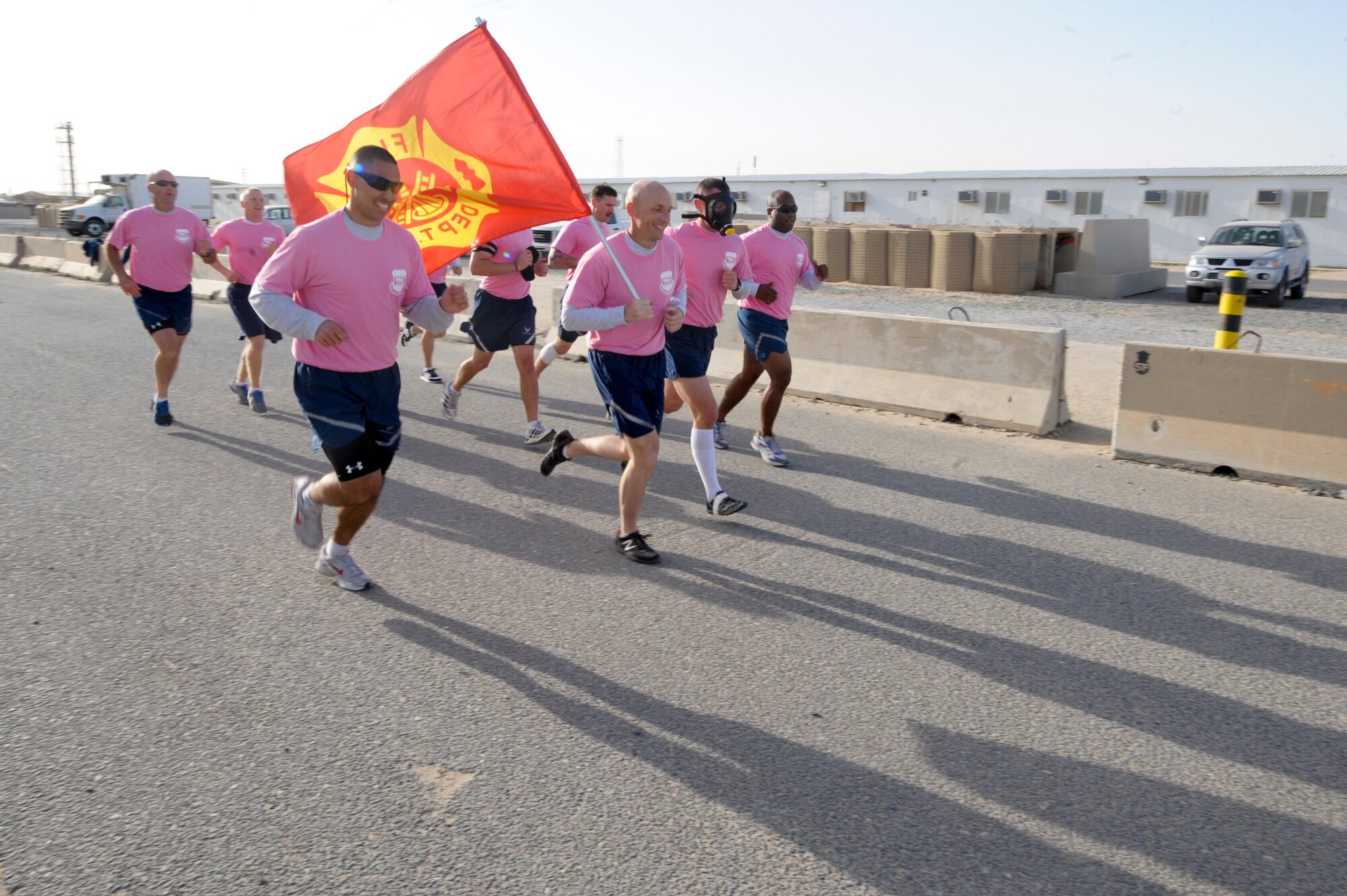 Firefighters from the 332nd Expeditionary Civil Engineer Squadron, run together carrying their flag during the "Cupid's Love Run" at an undisclosed location in Southwest Asia, Feb. 14, 2012. Some firefighters wear gas masks during the run to increase the difficulty. (U.S. Air Force photo by Staff Sgt. Joshua J. Garcia/Released)