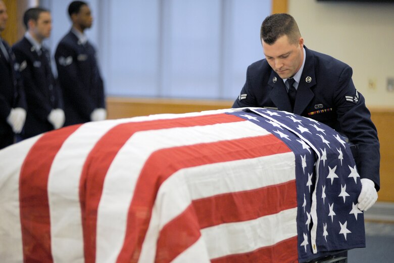 Airman 1st Class Shane Shaltry drapes the U.S. Flag over a casket as part of a training session for the 127th Wing Honor Guard at Selfridge Air National Guard Base, Mich., Feb. 10, 2012. In addition to the empty casket, volunteers acted as “grieving family members” to assist honor guard trainees learn the appropriate ceremonial honors to be rendered at a veteran’s funeral. The honor guard held a training session to qualify six new Airmen to serve as members of the unit. (U.S. Air Force photo by John S. Swanson)