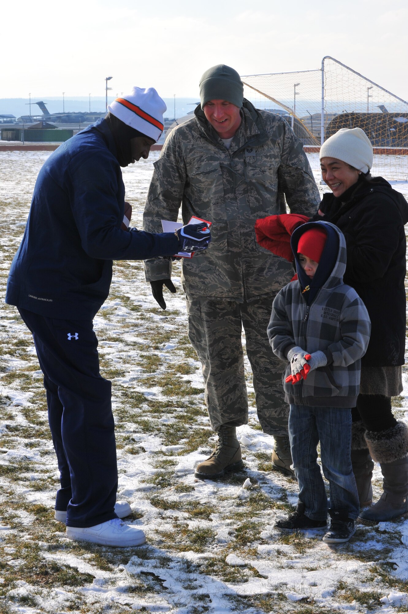 SPANGDAHLEM AIR BASE, Germany – O.J. McDuffie, left, retired Miami Dolphins wide receiver, autographs memorabilia for Staff Sgt. James Killian, 52nd Comptroller Squadron financial analyst; wife, Maria; and son, Justin, outside the Skelton Memorial Fitness Center here Feb. 10. The Miami Dolphins football players and cheerleaders toured various U.S. Air Force and Army bases in Europe as part of an Armed Forces Entertainment tour. The reason for the visit was to boost morale and entertain the base’s community. (U.S. Air Force photo by Airman 1st Dillon Davis/Released)