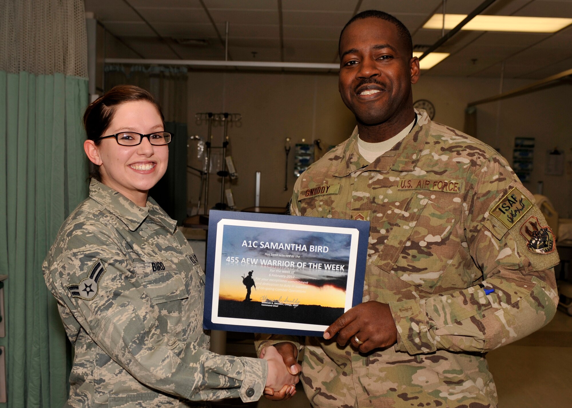 BAGRAM AIRFIELD, Afghanistan—Airman 1st Class Samantha Bird receives the Warrior of the Week award from Command Chief Master Sgt. Marcus Snoddy at Bagram Airfield, Afghanistan, Feb. 14, 2012. Bird is a medical technician with the 455th Expeditionary Medical Operations Squadron and earned the Warrior of the Week award for her hard work and dedication to excellence. (U.S. Air Force photo/ Airman 1st Class Ericka Engblom)