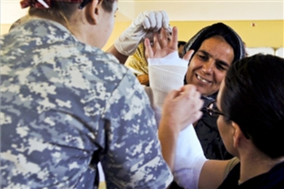 U.S. Army Maj. Leah Triolo, left, and U.S. Navy Lt. j.g. Ayleigh Amaya assist an Afghan in Afghanistan's Farah province, Feb. 11, 2012. Triolo is an orthopedic surgeon with the 67th Forward Surgical Team Airborne and Amaya is a physician’s assistant with Provincial Reconstruction Team Farah.