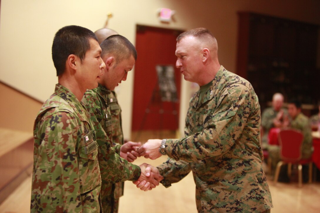Colonel Scott D. Campbell, commanding officer, 15th Marine Expeditionary Unit, presents his challenge coin to three soldiers from the Japanese Ground Self Defense Force for their hard work and dedication to Exercise Iron Fist 2012, during a social event, Feb. 14. The social event was held to celebrate the success of Exercise Iron Fist, a bilateral training event between the U.S. and Japanese Forces.
