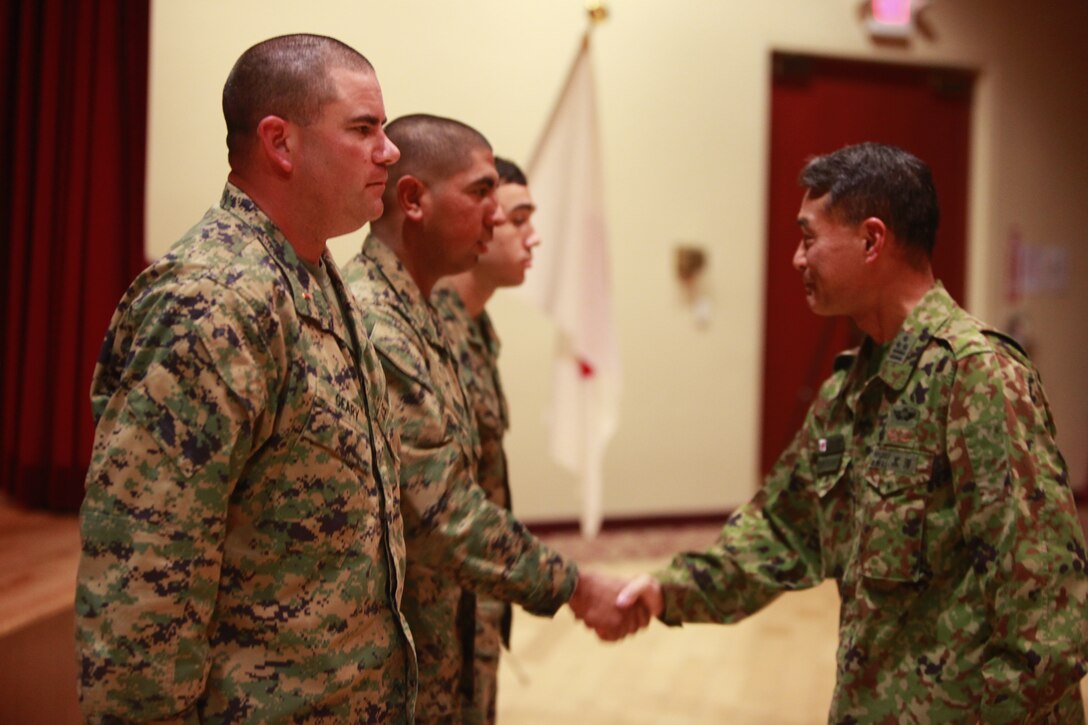 Japanese Army Col. Akira Kurosawa, commanding officer, Western Army Infantry Regiment, Japanese Ground Self Defense Force, presents his challenge coin to three Marines for their hard work and dedication to Exercise Iron Fist 2012, during a social event, Feb. 14. The social event was held to celebrate the success of Iron Fist, a bilateral training event between the U.S. and Japanese Forces.