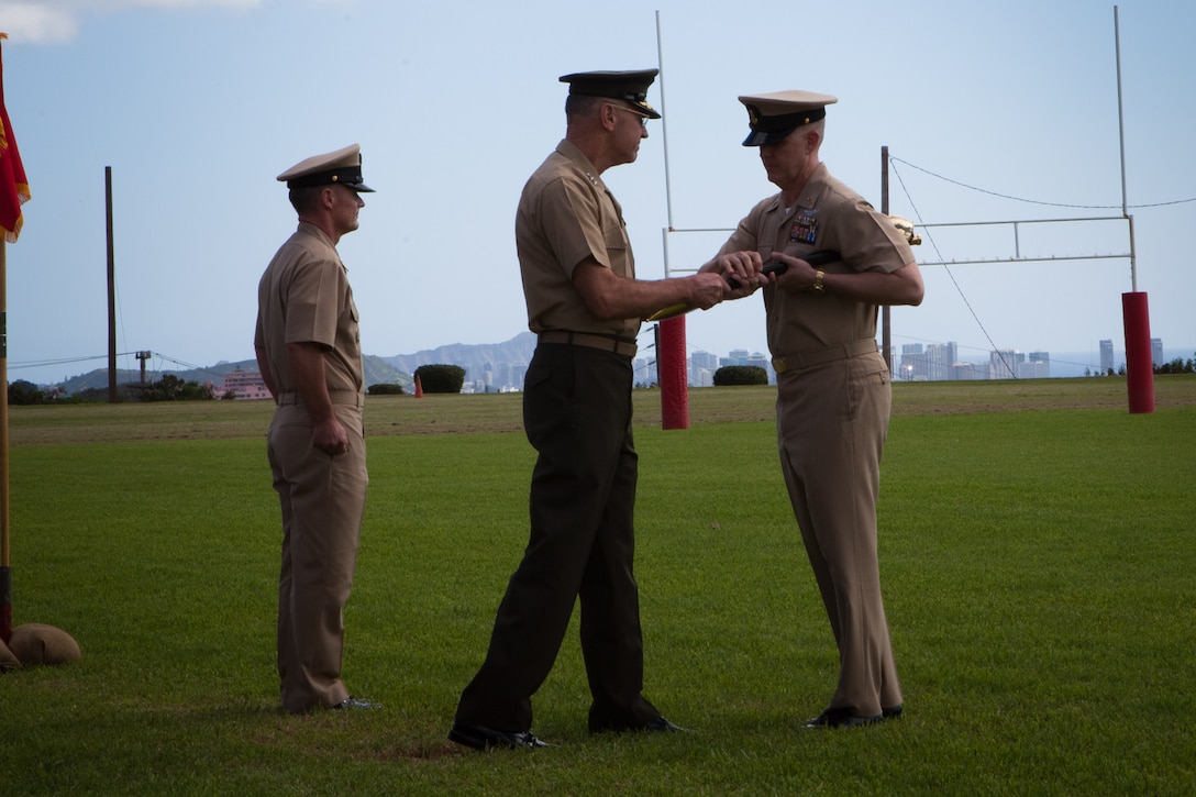 Master Chief Petty Officer Christopher Aldis receives a cutlass from Lt. Gen. Duane D. Thiessen, commander, U.S. Marine Corps Forces, Pacific, during a change-of-office ceremony at Bordelon Field here Jan. 20. Passing of the cutlass signifies the transfer of duties and responsibilities from one command master chief to another.