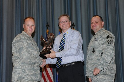 The annual Joint Base San Antonio-Randolph award winners were recognized during an awards ceremony at the base theater Feb. 14. Col. Scott Peel, 902nd Mission Support Group commander, left, and Chief Master Sgt. James Erwin, 902nd MSG superintendent, right, present the Non-Supervisor Civilian Category III of the Year Award to John McKinley from Air Education and Training Command. (U.S. Air Force photo/Rich McFadden) (released)