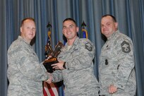The annual Joint Base San Antonio-Randolph award winners were recognized during an awards ceremony at the base theater Feb. 14. Col. Scott Peel, 902nd Mission Support Group commander, left, and Chief Master Sgt. James Erwin, 902nd MSG superintendent, right, present the Senior Non Commissioned Officer of the Year Award to Master Sgt. Arthur Wholly from the 902nd MSG (U.S. Air Force photo/Rich McFadden) (released)