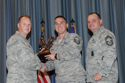 The annual Joint Base San Antonio-Randolph award winners were recognized during an awards ceremony at the base theater Feb. 14. Col. Scott Peel, 902nd Mission Support Group commander, left, and Chief Master Sgt. James Erwin, 902nd MSG superintendent, right, present the Senior Non Commissioned Officer of the Year Award to Master Sgt. Arthur Wholly from the 902nd MSG (U.S. Air Force photo/Rich McFadden) (released)