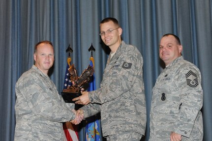 The annual Joint Base San Antonio-Randolph award winners were recognized during an awards ceremony at the base theater Feb. 14. Col. Scott Peel, 902nd Mission Support Group commander, left, and Chief Master Sgt. James Erwin, 902nd MSG superintendent, right, present the Honor Guard NCO of the Year Award to Tech. Sgt. Robert Bartlett from the Air Force Personnel Center. (U.S. Air Force photo/Rich McFadden) (released)