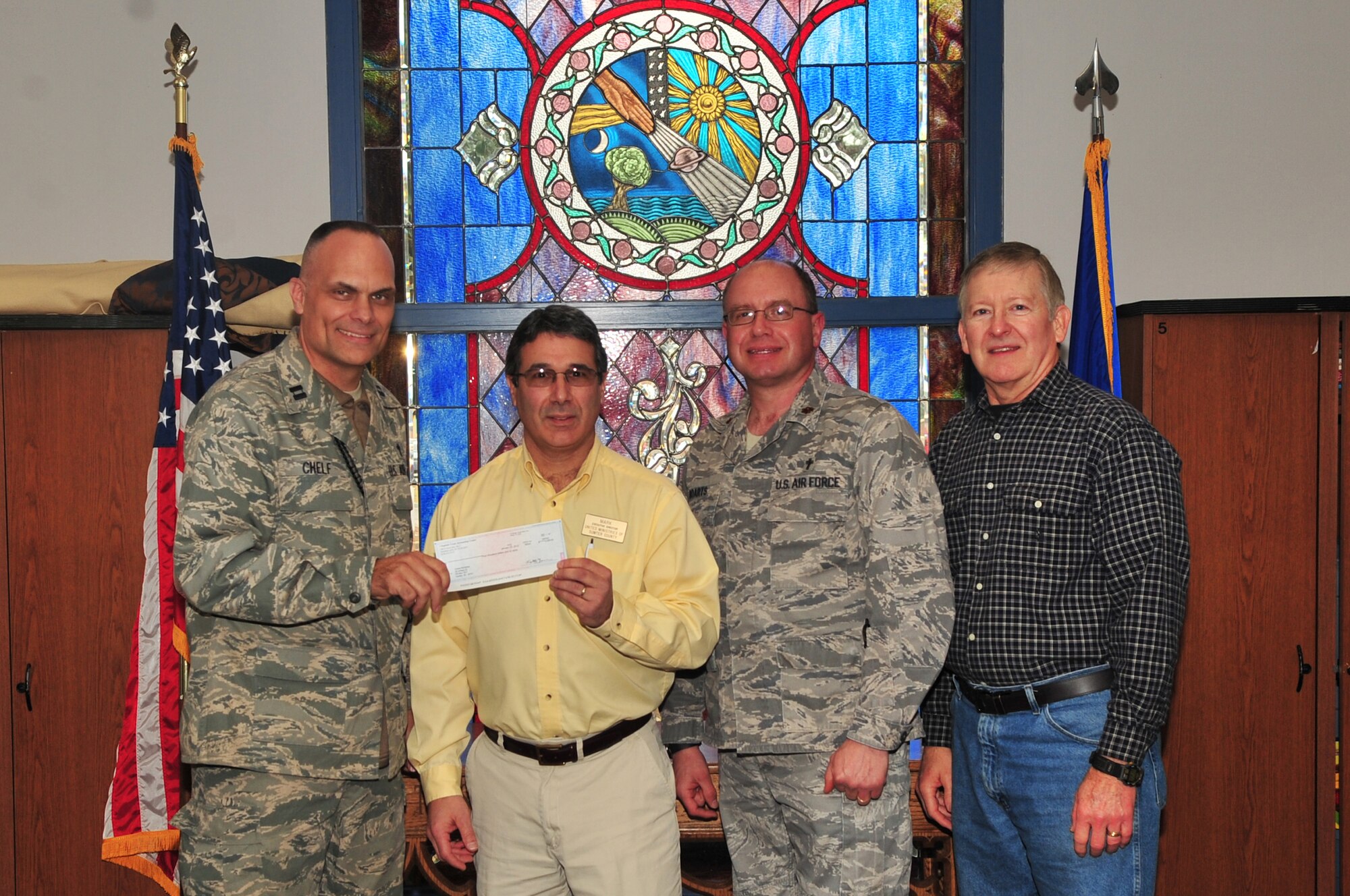 U.S. Air Force Capt. Kevin Chelf, 20th Fighter Wing  chaplain, Maj. Matthew Boarts, 20th Fighter Wing chaplain, and Hugh Wilson, young adult ministry coordinator, present a check to Mark Champagne, United Ministries of Sumter, executive director, Shaw Air Force Base, S.C., Feb.14, 2012.The check donated to United Ministries of Sumter was worth $4,000 dollars. Team Shaw pulled together to make the donation happen. The protestant advisory council helped decide how the donation would be distributed. (U.S. Air Force photo by Airman 1st Class Ashley L. Gardner/ Released)
