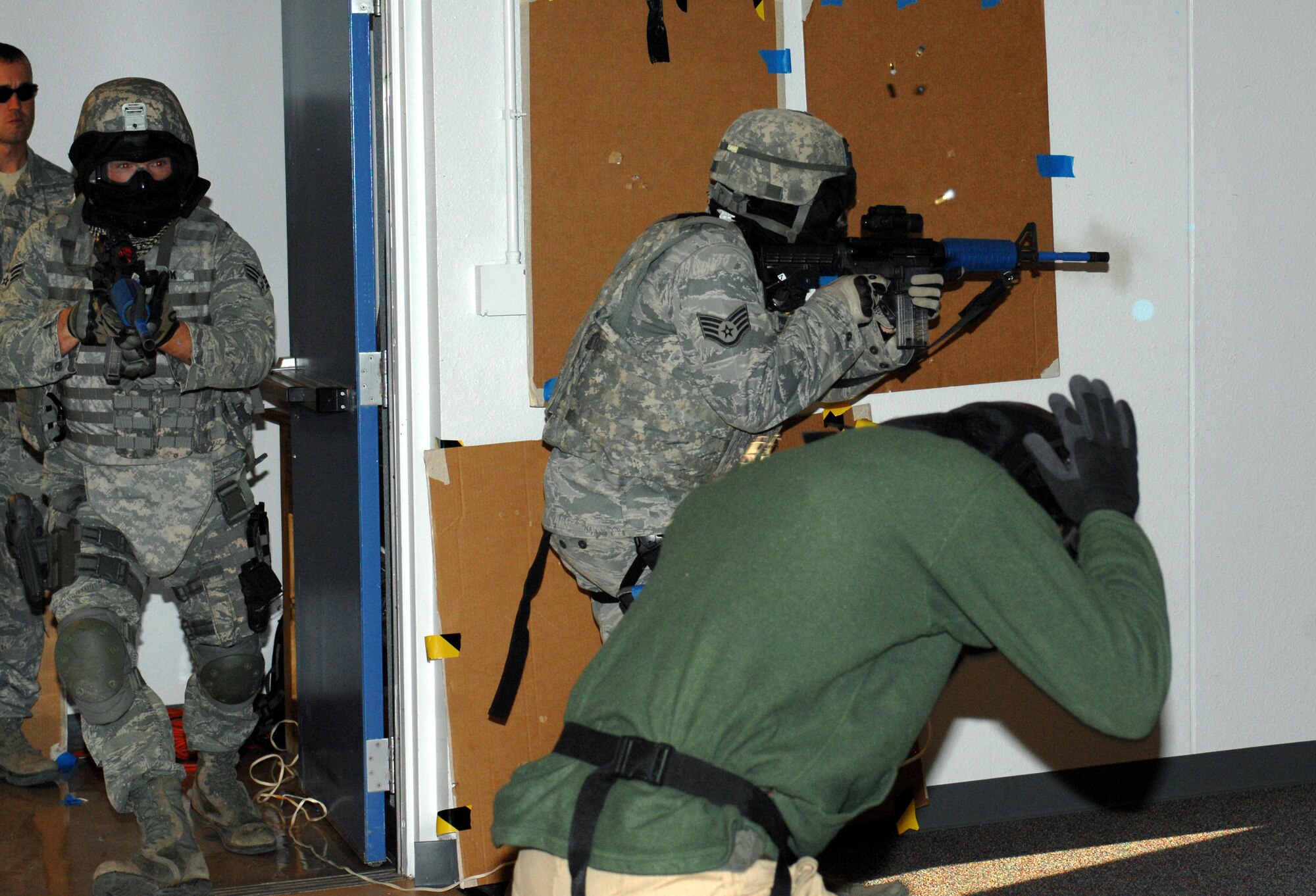 Two Airmen from the 355th Security Forces Squadron rush into a room full of civilians and hostiles, identify friend from foe and take swift action during an active shooter training exercise at Davis-Monthan Air Force Base, Ariz., Feb. 9. A simunition is a non-lethal round which leaves visible marks when hit. (U.S. Air Force photo by Airman 1st Class Michael Washburn/Released)