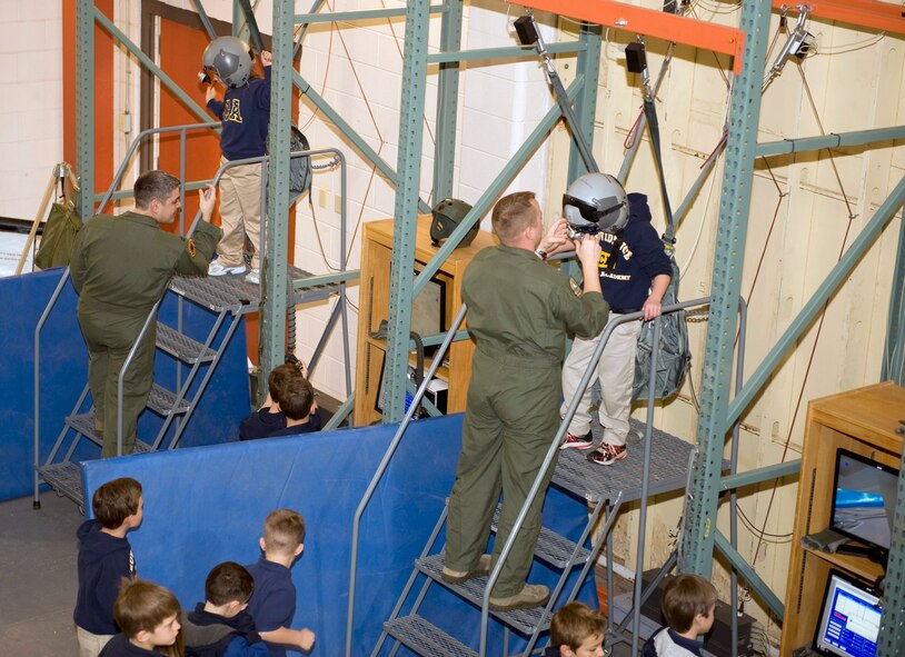 Capt. Kenneth Byrd, 2nd Operations Support Squadron, left, and Tech. Sgt. Matthew Searby, 2 OSS Survival, Evasion, Resistance and Escape specialist, help children in and out of a parachute simulation harness on Barksdale Air Force Base, La., Feb. 14. The simulator is used to teach service members how to properly use a parachute in various situations. (U.S. Air Force photo/Airman 1st Class Benjamin Gonsier)(RELEASED)