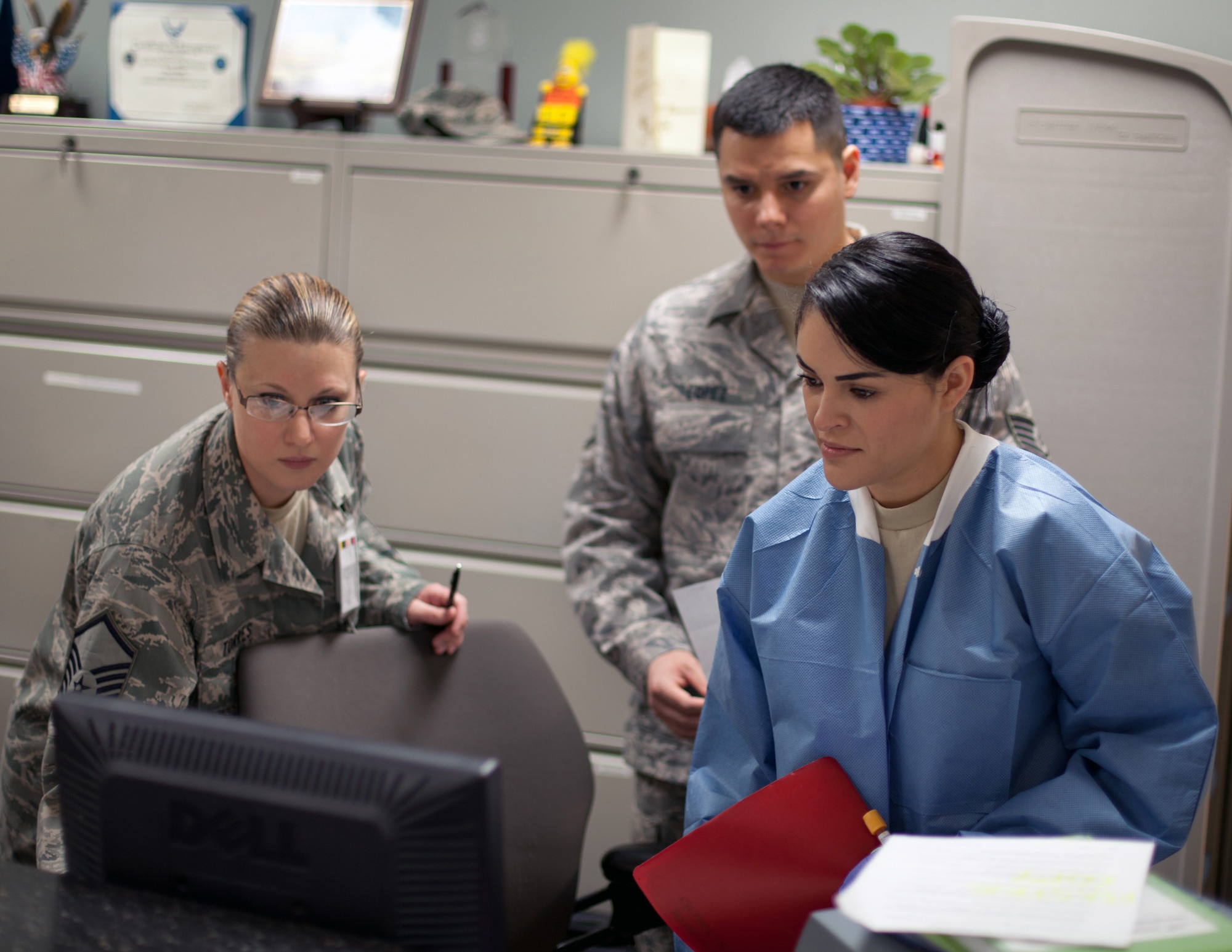 Master Sgt. Sarah Torres, noncommissioned officer in charge of the 349th Aeromedical Medicine Squadron's clinical laboratory, helps Staff Sgt. Daniel Lopez and Senior Airman Veronica Barros work through a computer procedure at the front window of the lab at David Grant USAF Medical Center. (U.S. Air Force photo / Lt. Col. Robert Couse-Baker)