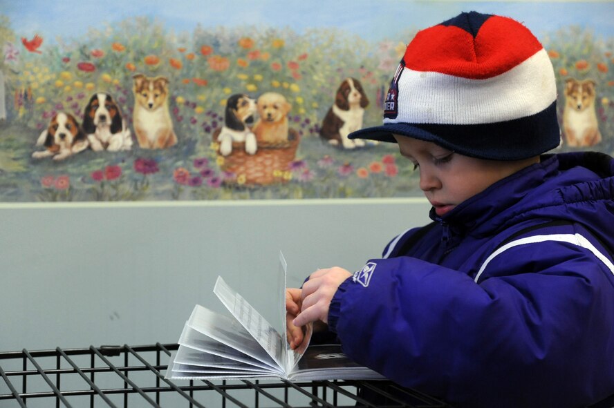 Pierce McCardle, 5, flips through a photo album of Demi, a shepard mix, at a Diamonds in the Ruff Dog wash and adoption event at Cuts-4-Muttz in Goldsboro, N.C., Feb. 11, 2012. Demi is a 1-year-old dog available for adoption. McCardle, son of U.S. Air Force Staff Sgt. David McCardle, 4th Civil Engineer Squadron dorm leader, is from Goldsboro, N.C. (U.S. Air Force photo/Senior Airman Whitney Stanfield/Released)