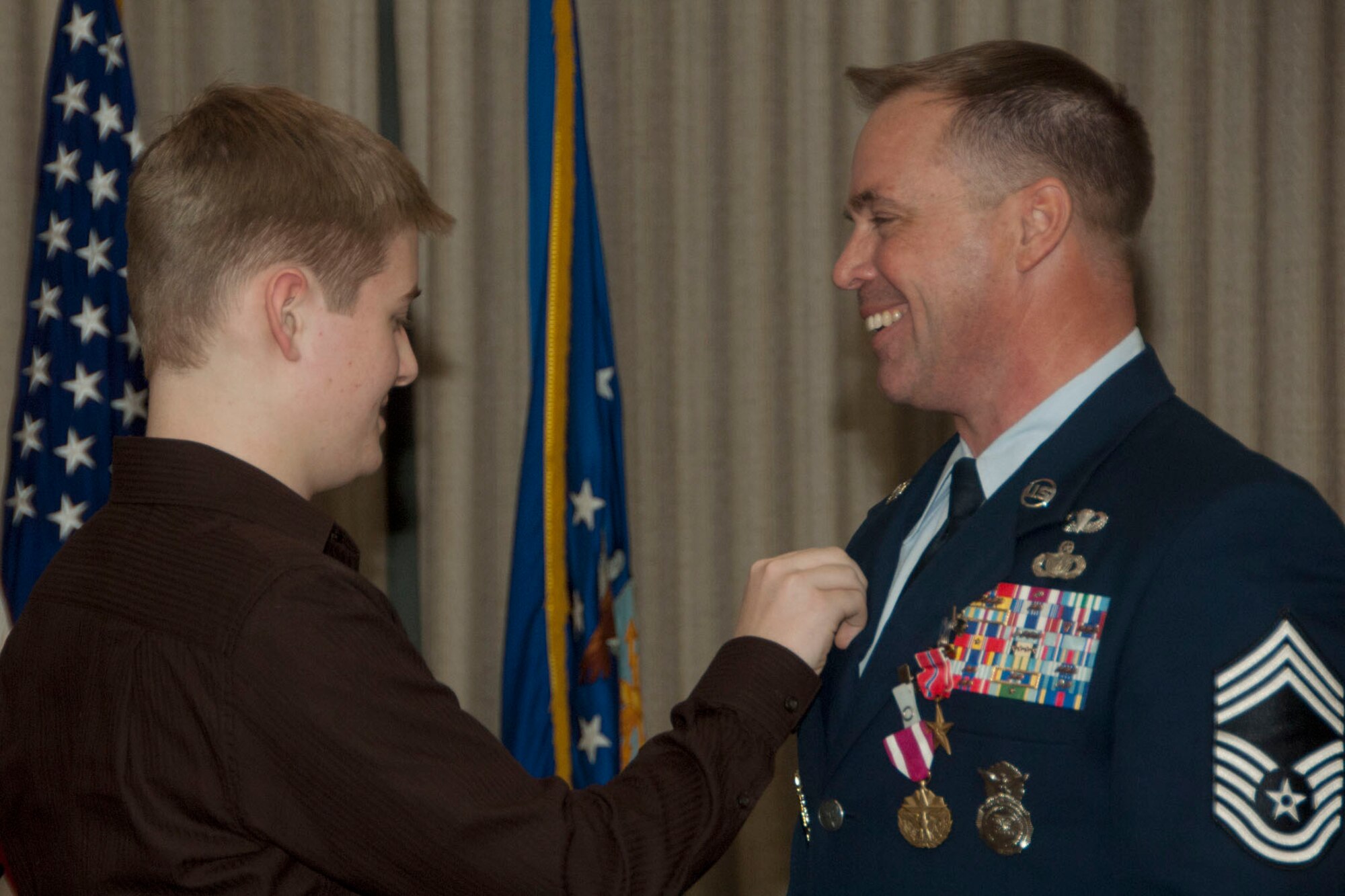 Chief Master Sgt. Edward Madden’s son, Quinton, pins a medal on him during his retirement ceremony at the Hanscom Conference Center Feb. 10. Chief Madden, 66th Security Forces Squadron manager, retired after serving for 29 years. (U.S. Air Force photo by Linda LaBonte Britt)