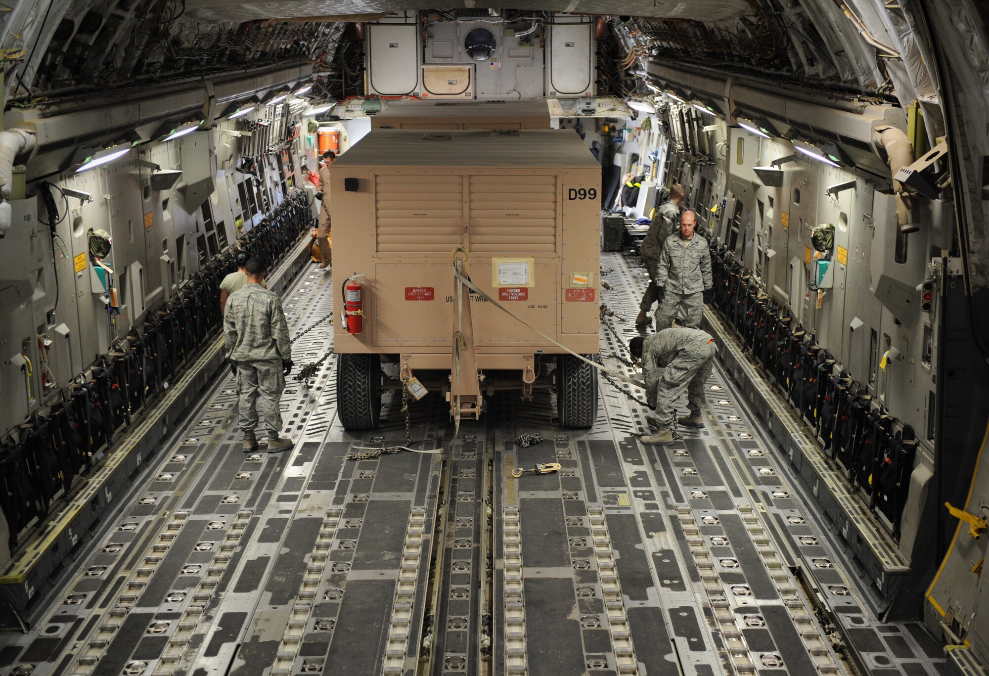 SOUTHWEST ASIA – Airmen from the 8th Expeditionary Air Mobility Squadron ramp section secure straps holding a generator in place inside a C-17 Globemaster III here Feb. 11, 2012. The Airmen load about 12,000 tons of cargo into aircraft every month. (U.S. Air Force photo/Staff Sgt. Nathanael Callon)