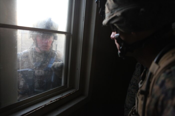 Marines with Charlie Company, Battalion Landing Team 1st Battalion, 2nd Marine Regiment, 24th Marine Expeditionary Unit, talk tactics through a window before pushing to their next objective during a training raid at Camp Lejeune’s Military Operations in Urban Terrain Compound, Feb. 15. The raid was part of Certification Exercise (CERTEX) - the final at-sea training exercise for the 24th MEU with the Iwo Jima Amphibious Ready Group which took place Jan. 27-Feb. 16, and included a series of missions intended to evaluate and certify the units for their upcoming deployment.