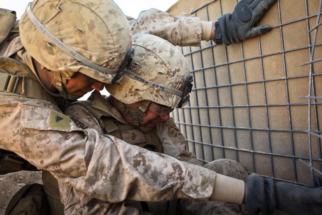 Lance Cpl. Paul Flores (left), and PFC Travis Rezba, both combat engineers with Alpha Company, 9th Engineer Support Battalion, use bolt cutters to cut the mesh wiring on a HESCO barrier at Firebase Saenz, Helmand province, Dec. 14. FB Saenz is the first of several patrol bases being demilitarized by the Marines of 9th ESB throughout the month of December.