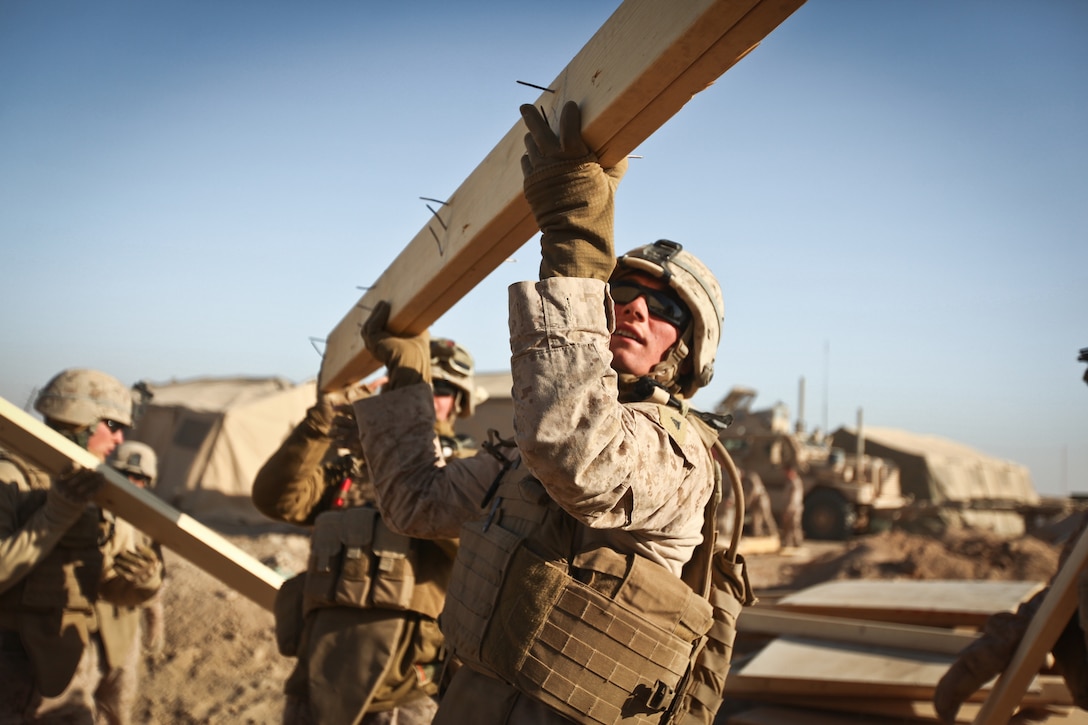Lance Cpl. Christopher Miller, a combat engineer with Alpha Company, 9th Engineer Support Battalion, and a native of Emmett, Mich., throws a piece of wood from a tent into the back of a dump truck at Support Battalion, guide a bulldozer as it moves the berm surrounding a guard post at Firebase Saenz, Helmand province, Dec. 15. FB Saenz is the first of several patrol bases being demilitarized by the Marines of 9th ESB throughout the month of December.