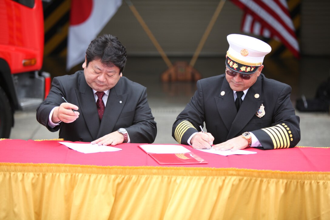 Tsuyoshi Gibu, Kin Town mayor, and Scott Minakami, fire chief for the Camp Hansen Fire Department, sign a mutual support agreement at the fire department on Camp Hansen Jan. 30. The agreement is a proactive step to prepare the fire departments of Kin Town and Camp Hansen for any emergency.