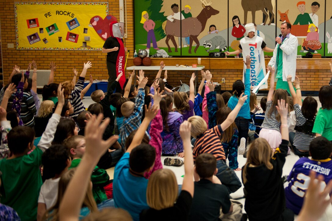 Capt. Bradley Harrelson, also known as Dr. Juggles, speaks about the importance of oral health with Staff Sgt. Kristen Randall, acting as Sparkle the toothbrush, and Senior Airman Francis Morales, acting as Tubey the toothpaste, at Horace Mann Elementary students during Children’s Dental Health Month in Rapid City, S.D., Feb. 9, 2012. Dr. Juggles and his staff, assigned to the 28th Medical Operations Squadron traveled to several elementary schools in the area educating children on the importance of oral health. (U.S. Air Force photo by Airman 1st Class Kate Thornton/Released)