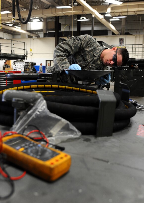 Senior Airman Robert Greear, 28th Maintenance Squadron aerospace ground equipment maintenance mechanic, applies rubber adhesive to a fuel collection funnel at Ellsworth Air Force Base, S.D., Feb. 9, 2012. AGE mechanics repair, inspect and perform preventive maintenance on motors, generators, air conditioners, hydraulic test stands, air compressors, bomb lifts, heaters, and other support equipment. (U.S. Air Force photo by Airman 1st Class Zachary Hada/Released)