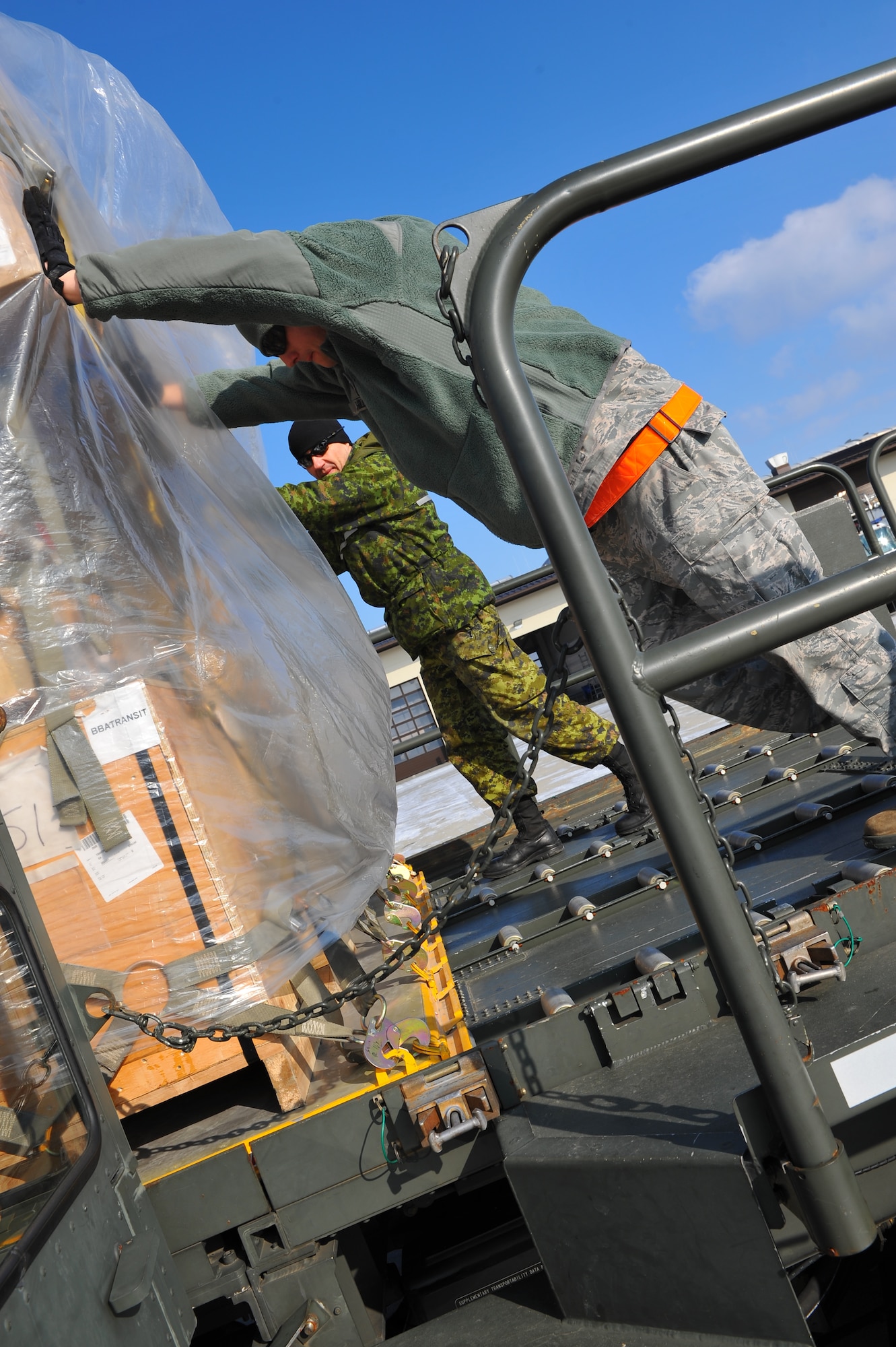 SPANGDAHLEM AIR BASE, Germany – Senior Airman Robert Hill, right, 726th Air Mobility Squadron aircraft services specialist, and Warrant Officer Al Sadler, Canadian Forces Detachment Spangdahlem services specialist, push a pallet off a 60K Tunner outside the squadron’s maintenance shop here Feb. 10. AMS employs more than 100 Airmen to complete its three missions of aerial port, command and control and maintenance. These missions are essential to executing the mobilization of service members and cargo in support of operations in Europe and bases in U.S. Central Command. (U.S. Air Force photo by Airman 1st Class Dillon Davis/Released)