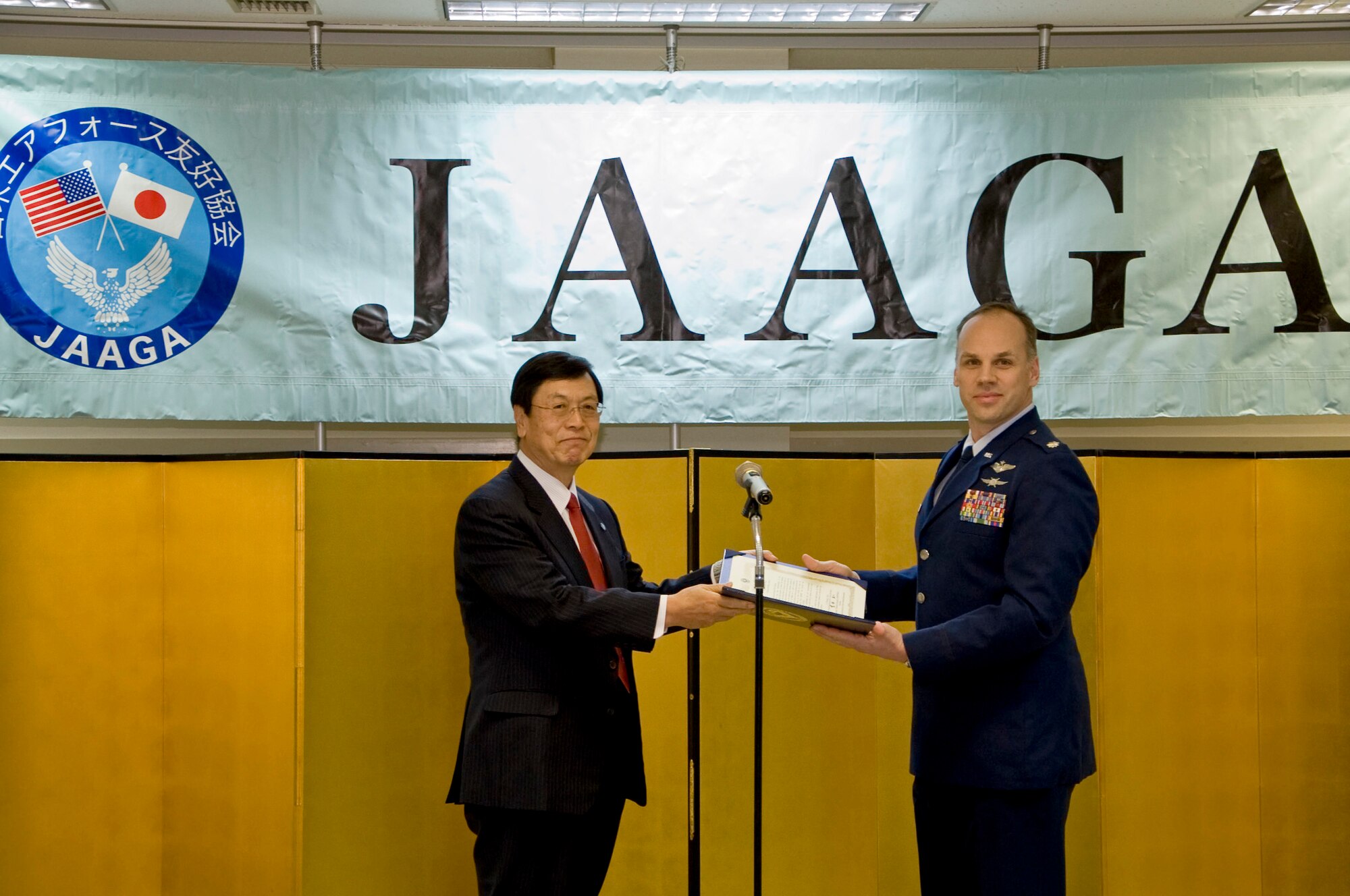 IRUMA AIR BASE, Japan -- The Japan-America Air Force Goodwill Association president gives the JAAGA Award to Lt. Col. Peter Kelley (right), 374th Mission Support Group vice commander, Feb. 10, 2012, at Iruma Air Base, Japan. Kelley won the award for coordinating 25 bilateral construction projects to enhance cooperation between the Air Defense Command and U.S. Forces, Japan. (U.S. Air Force photo/Airman 1st Class John D. Partlow)