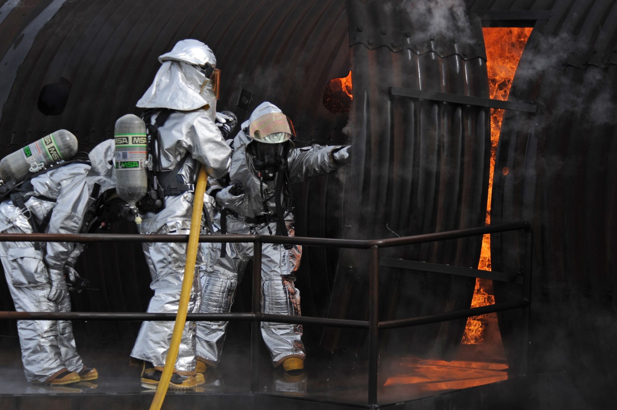 Firefighters from the 2nd Civil Engineer Squadron prepare to enter a burning mock aircraft on Barksdale Air Force Base, La., Feb. 16. Temperatures from the mock aircraft could reach up to 2,000 degrees Fahrenheit. Firefighters must use caution when entering high temperature areas; any liquids inside the suit can turn into steam causing serious harm or even death. (U.S. Air Force photo/Airman 1st Class Micaiah Anthony)(RELEASED)
