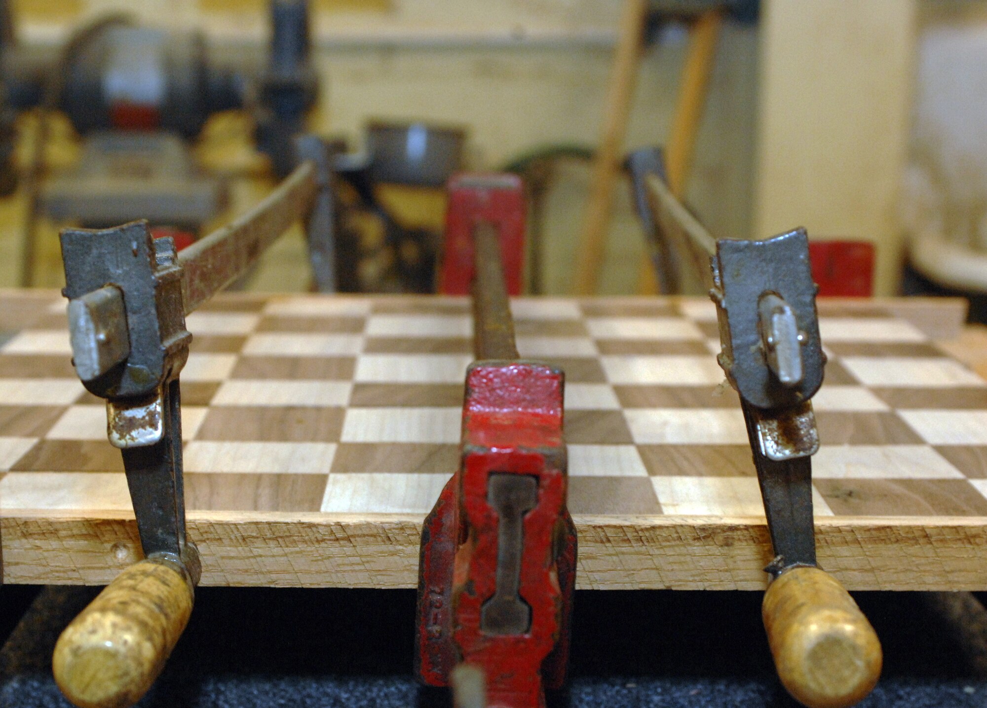 A two-tone chess board pressed between clamps dries at the Hobby Shop on Barksdale Air Force Base, La., Feb. 15. A variety of objects are made at the Hobby Shop by wood-working experts and Airmen qualified to use the Hobby Shop tools. (U.S. Air Force photo/Airman 1st Class Joseph A. Pag?n Jr.)(RELEASED)
