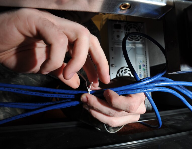 Senior Airmen Jeffery Davis, 744th Communication Squadron radio frequency transmission technician, harnesses ethernet cords Feb. 17 at Francis T. Evans Elementary School, Clinton, Md. More than 100 feet of wire was used to connect the 87 donated computers, in order to reduce tripping hazards all wires are bond together. (U.S. Air Force photo by Staff Sgt. Christopher Ruano)