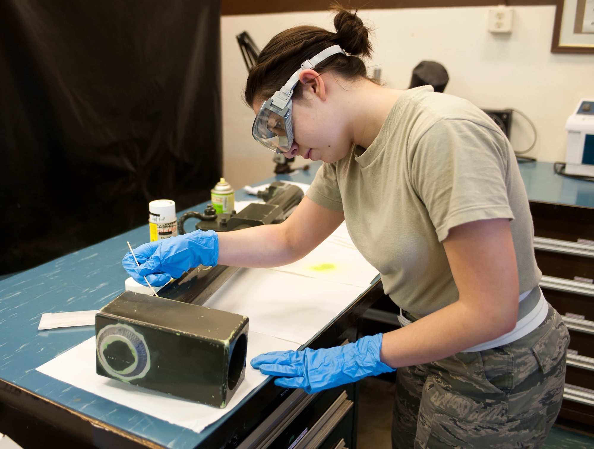 Airman 1st Class Samantha Watkins, 28th Maintenance Squadron non-destructive inspection apprentice, applies a florescent penetrant to a weapons pylon lift assembly during an inspection at Ellsworth Air Force Base, S.D., Feb. 10, 2012. The penetrant seeps into any potential cracks so they become visible during ultra-violet inspection. (U.S. Air Force photo by Airman 1st Class Zachary Hada/Released)