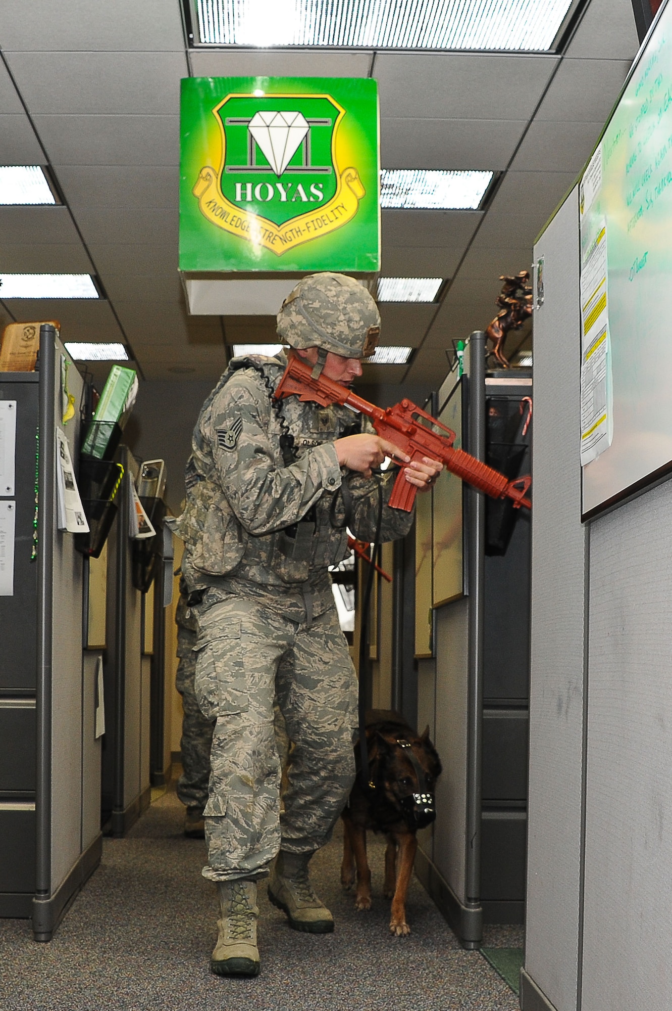 Holding a simulated weapon, Staff Sgt. Brent Olson and military working dog Akim of the K-9 unit from 42nd Security Forces sweep building 1487 in search of a simulated active shooter Tuesday. The exercise assessed the ability of base personnel and emergency response teams to react to reports of a gunman on the installation. Maxwell and Gunter hold periodic exercises to ensure base personnel are prepared to respond to an assortment of challenges, including natural disasters, accidents and other emergencies. (Air Force photo/Donna Burnett)