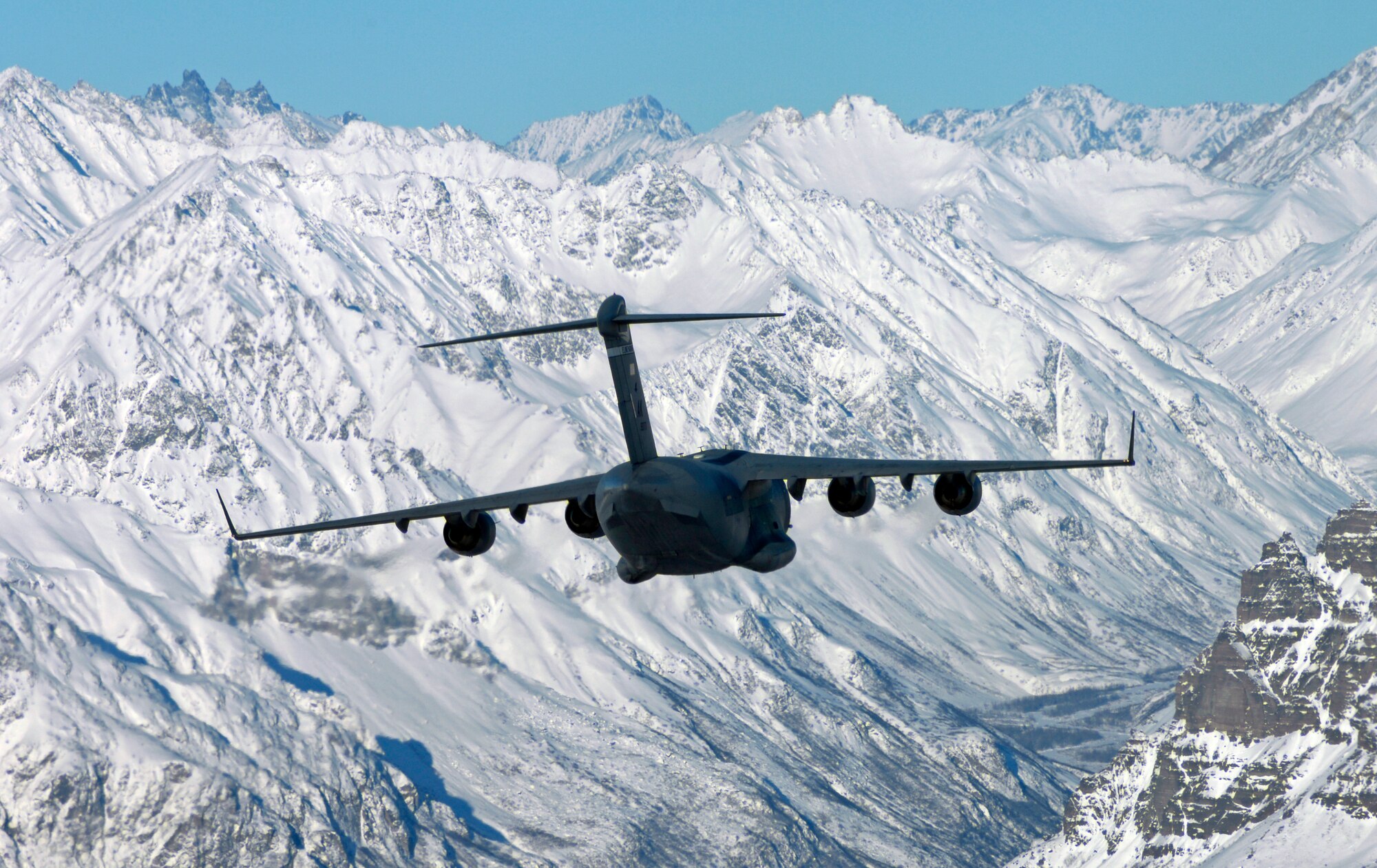 A C-17 Globemaster III from the 517th Airlift Squadron flies over an Alaska mountain range, before dropping Soldiers from the 6th Engineer Battalion (Combat) (Airborne) Feb. 7. (U.S. Air Force photo/Tech Sgt. Brian Ferguson)