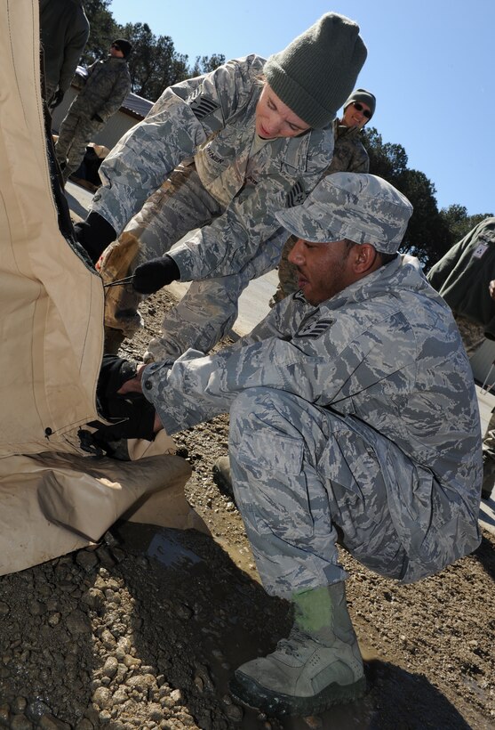 U.S. Air Force Tech. Sgt. Laura Fournier, 633rd Force Support Squadron shift manager, and Staff Sgt. Jarenlee Brown, 633rd FSS lodging technician, assemble a temporary protection tent during the phase II operational readiness exercise at Langley Air Force Base, Va., Feb. 13, 2012. Airmen participated in the phase II ORE to practice for upcoming exercises and inspections. (U.S. Air Force photo by Airman 1st Class Teresa Cleveland/Released)