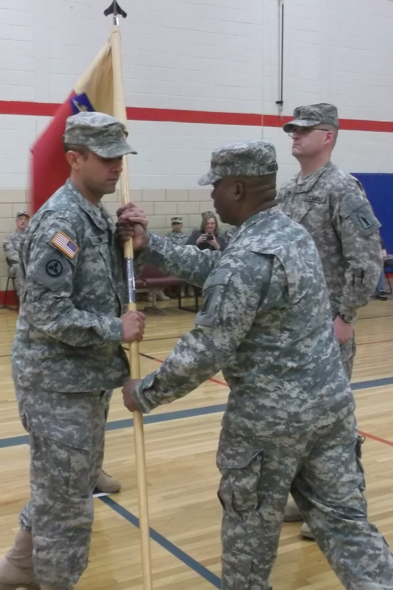 Maj. Wesley Melton, (left) from Spokane, Mo., 77th Sustainment Brigade, Headquarters and headquarters company outgoing commander receives the unit colors from First Sergeant Gregory Isidore, HHC first sergeant, during the units change of command ceremony held here Feb. 12. Melton relinquishes command of the unit to Capt. David Rodriquez (right). The unit recently returned from a deployment to Iraq in support of Operation New Dawn. During their nine month tour the 77th HHC, worked to maintain manpower responsibilities for the 77th STB in Balad, Iraq. Lt. Col. Kim Barrington 77th Special Troops Battalion presided over the ceremony. (U.S. Army photo by Sgt. Terri Reese/Released)